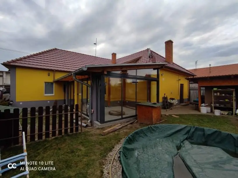 Zasklenie terasy s antracitovou konštrukciou RAL 7016 a posuvným hliníkovým systémom pri žltom dome v Pezinku, pohľad z boku